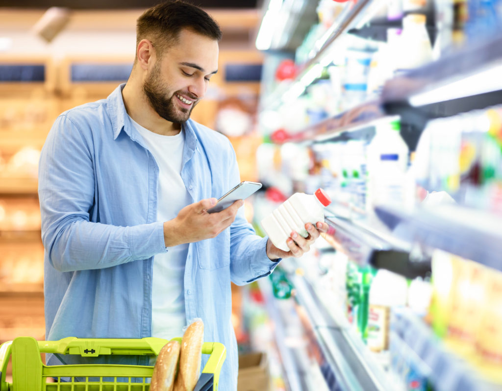 Homme scannant un produit dans un supermarché avec son téléphone