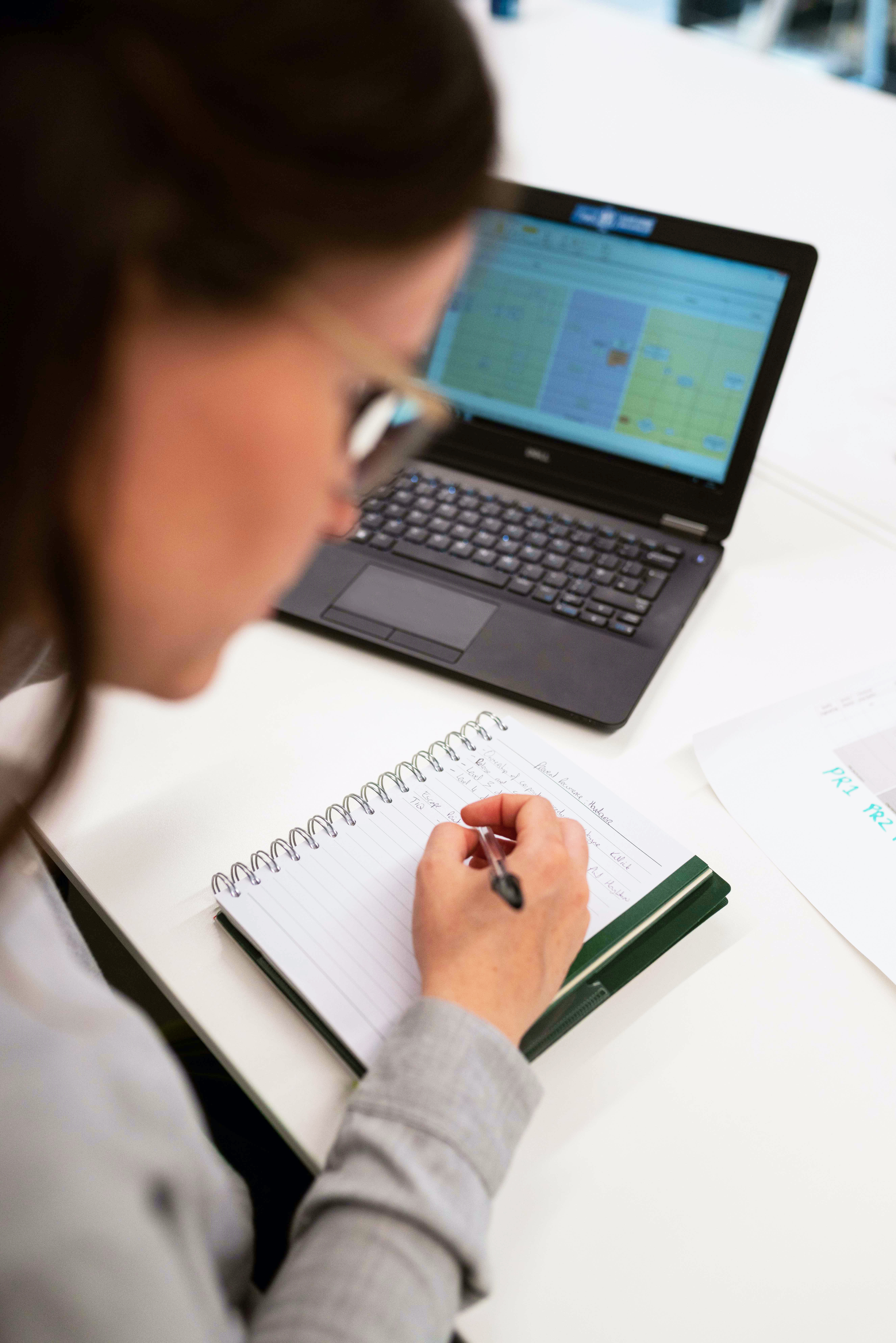 Femme écrivant à côté d'un ordinateur avec un tableur Excel